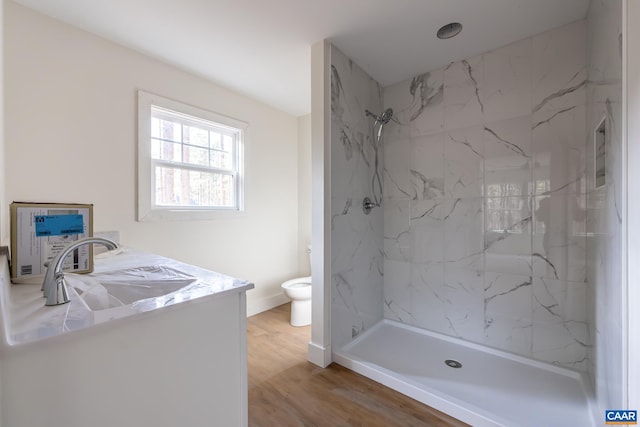 full bathroom featuring toilet, wood finished floors, vanity, baseboards, and a marble finish shower