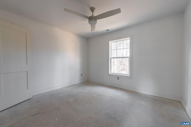 empty room with concrete flooring, visible vents, ceiling fan, and baseboards