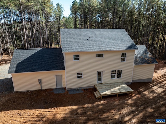 back of property with roof with shingles and a deck