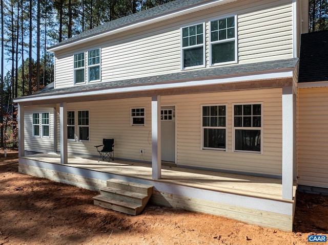 back of house featuring roof with shingles