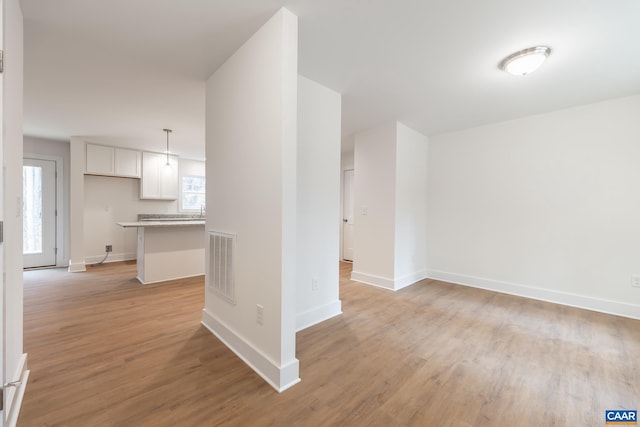 interior space featuring light wood-style floors, baseboards, and visible vents