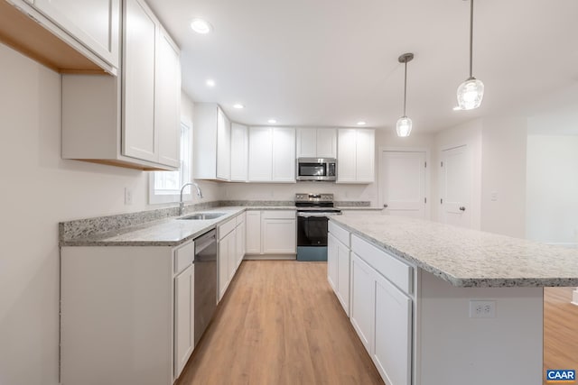 kitchen featuring stainless steel appliances, a sink, white cabinetry, and a center island