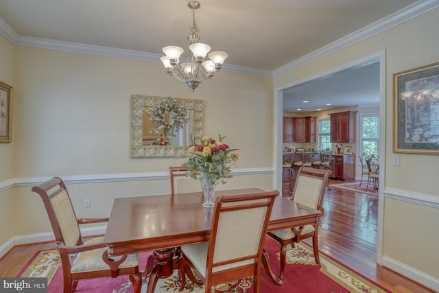 dining area featuring crown molding, an inviting chandelier, and light hardwood / wood-style flooring