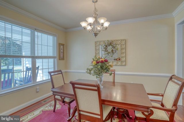 dining space with visible vents, wood finished floors, crown molding, and a chandelier