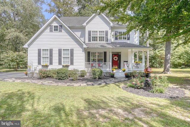 view of front facade with covered porch, a shingled roof, and a front lawn