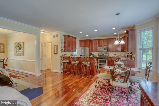 dining room with ornamental molding and light hardwood / wood-style floors