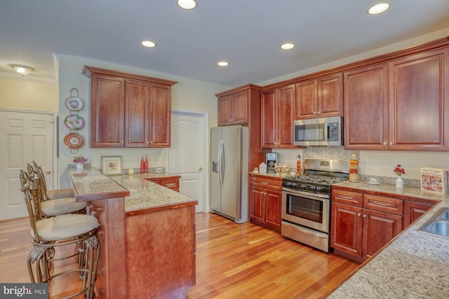 kitchen with a kitchen breakfast bar, stainless steel appliances, light countertops, and light wood-style floors