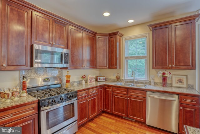 kitchen featuring tasteful backsplash, appliances with stainless steel finishes, sink, and light wood-type flooring