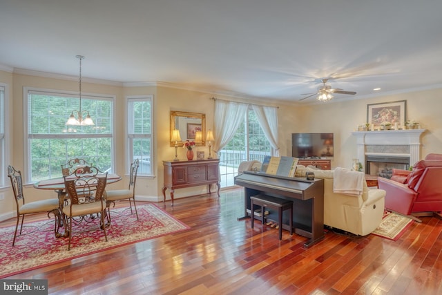 living room with hardwood / wood-style flooring, ornamental molding, and ceiling fan with notable chandelier