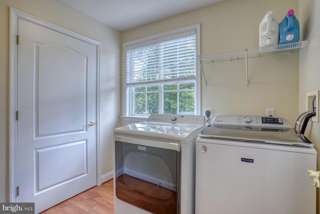 laundry room featuring washing machine and clothes dryer, laundry area, and light wood-style flooring