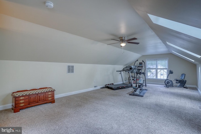 exercise area with visible vents, lofted ceiling with skylight, light carpet, baseboards, and ceiling fan