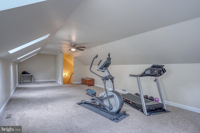 exercise area with visible vents, baseboards, carpet flooring, vaulted ceiling with skylight, and a ceiling fan