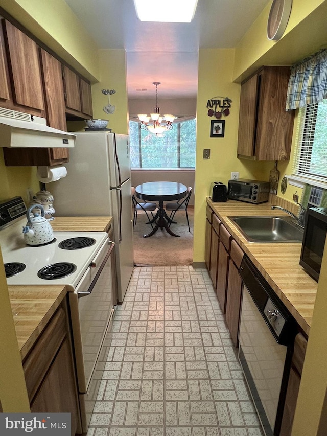 kitchen featuring white electric range oven, a sink, under cabinet range hood, dishwasher, and a notable chandelier