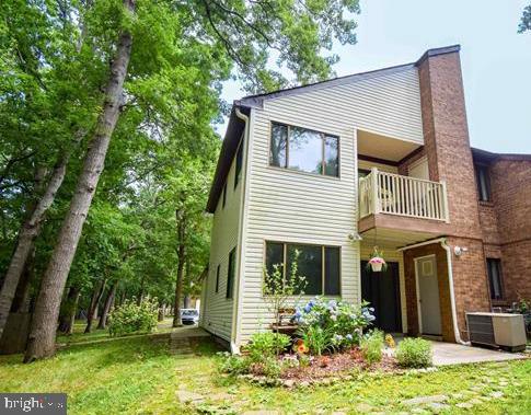 back of property with a balcony, cooling unit, a lawn, and a chimney