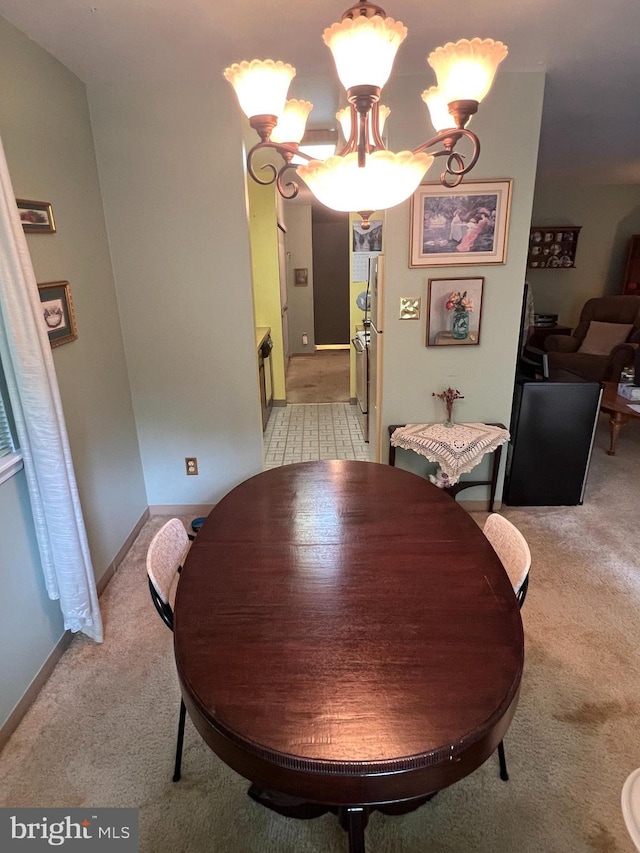 dining room featuring a notable chandelier, light colored carpet, and baseboards