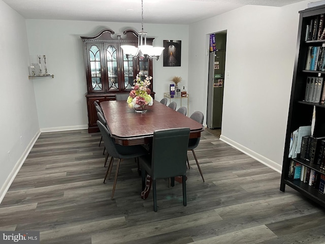 dining space with a chandelier, baseboards, and wood finished floors