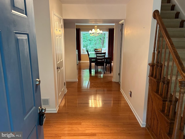 corridor with an inviting chandelier and light hardwood / wood-style floors