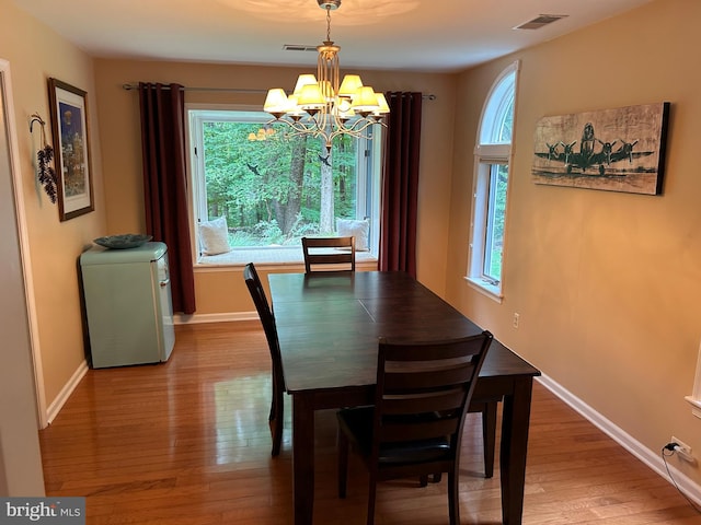 dining area with wood-type flooring and an inviting chandelier