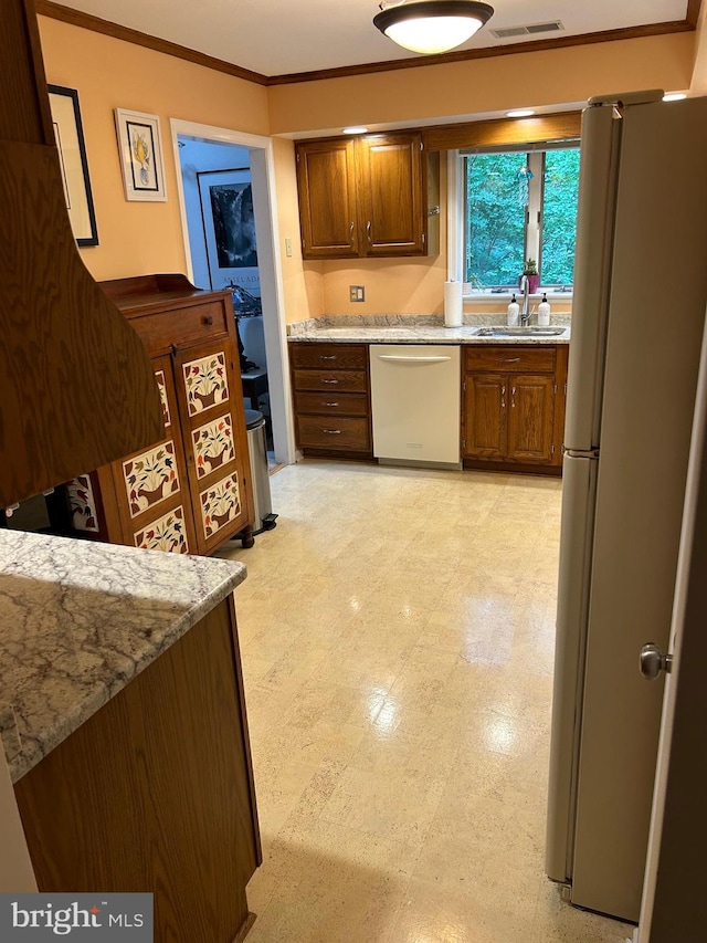 kitchen featuring crown molding, light stone countertops, sink, white fridge, and stainless steel dishwasher