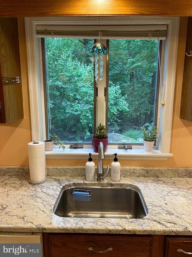 interior details with dishwasher, light stone counters, and sink