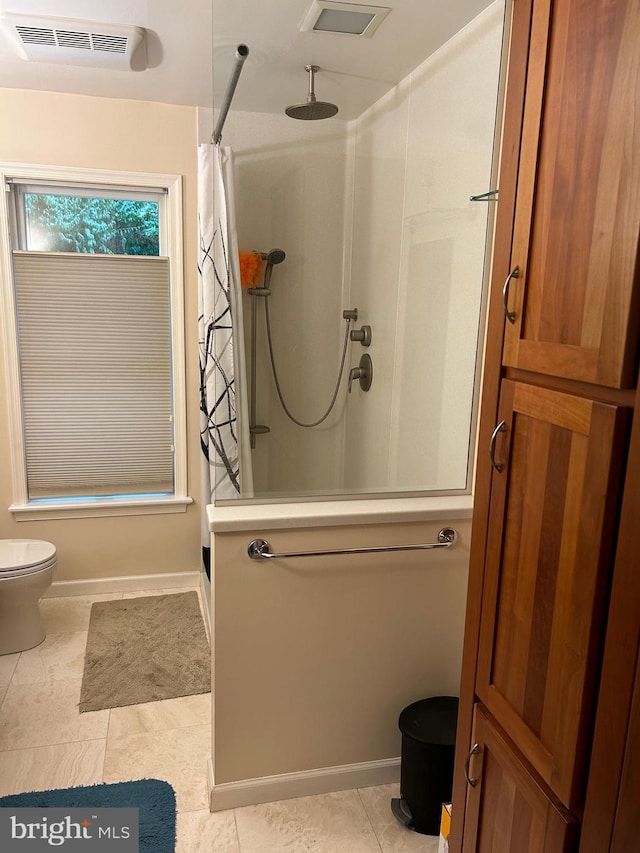 bathroom featuring a shower, tile patterned flooring, and toilet