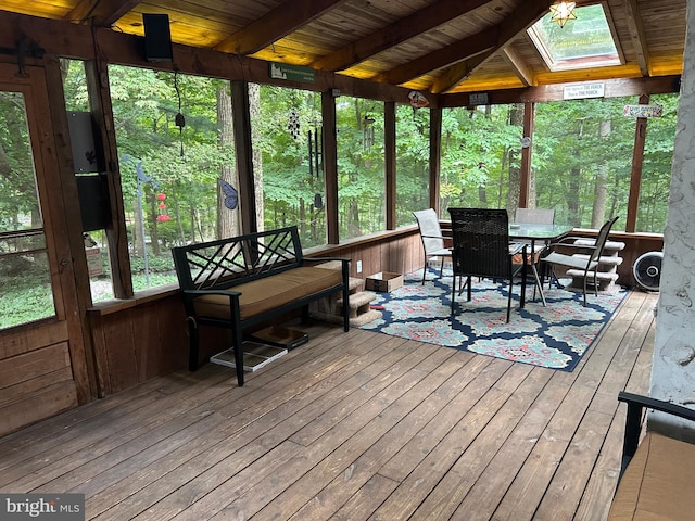 sunroom / solarium featuring a skylight, beamed ceiling, and wooden ceiling