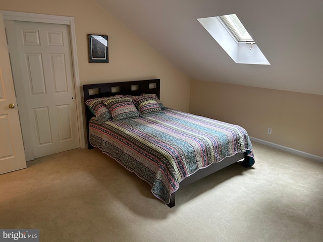 carpeted bedroom featuring lofted ceiling with skylight