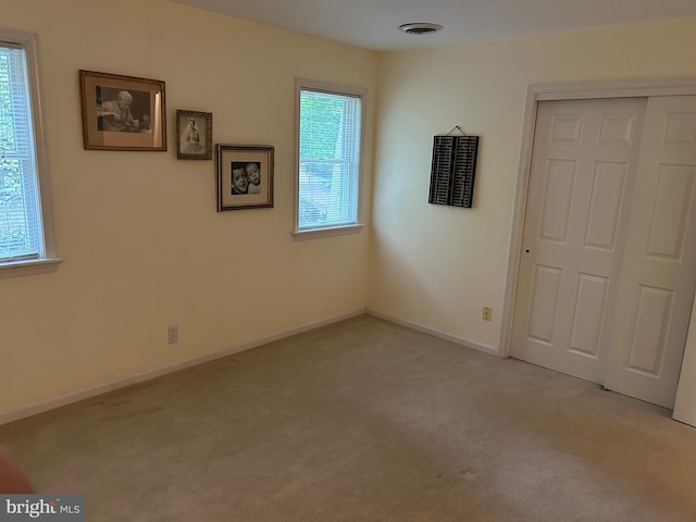 unfurnished bedroom with a closet and light carpet