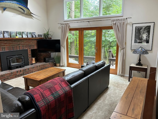 living room featuring a wood stove, light colored carpet, plenty of natural light, and a brick fireplace