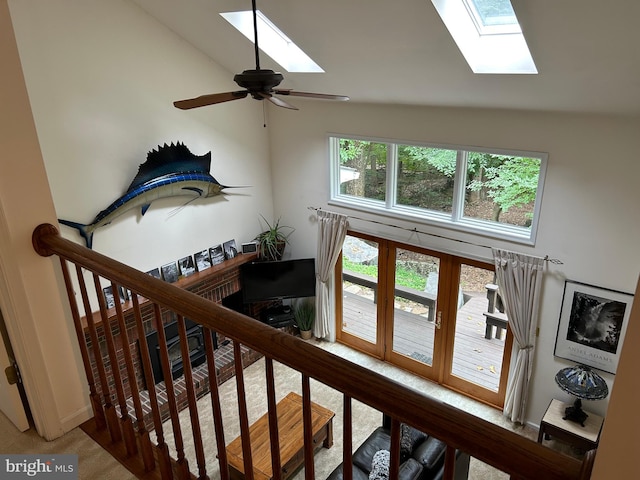 staircase with high vaulted ceiling, a skylight, ceiling fan, and carpet