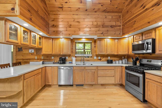 kitchen featuring light hardwood / wood-style flooring, appliances with stainless steel finishes, a breakfast bar, sink, and high vaulted ceiling