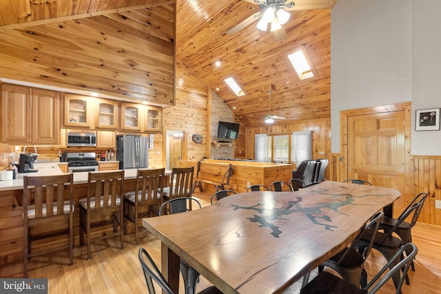 dining space featuring high vaulted ceiling, a skylight, ceiling fan, and light hardwood / wood-style floors