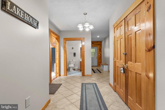 tiled foyer entrance featuring a textured ceiling and a notable chandelier