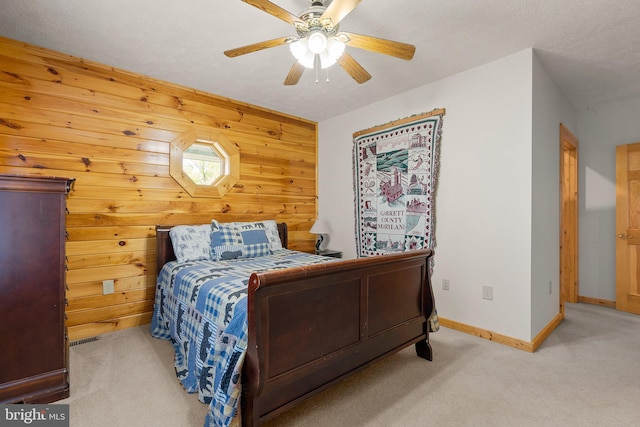 carpeted bedroom featuring a textured ceiling, ceiling fan, and wood walls