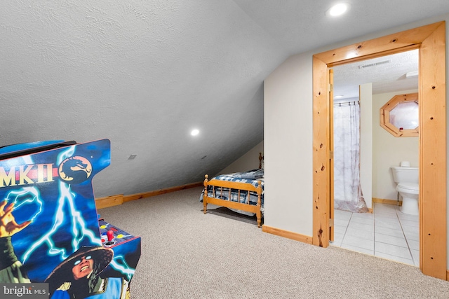 bedroom with lofted ceiling, connected bathroom, light colored carpet, and a textured ceiling