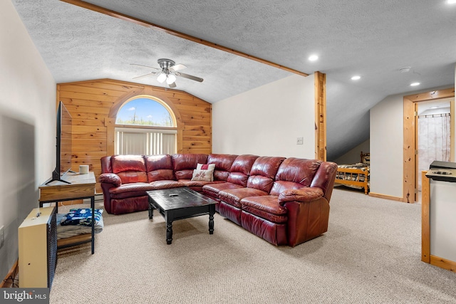 carpeted living room with vaulted ceiling, a textured ceiling, wood walls, and ceiling fan