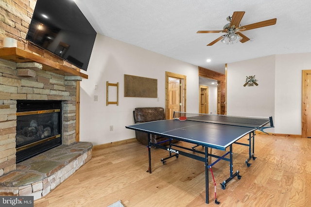 game room featuring ceiling fan, light wood-type flooring, and a fireplace