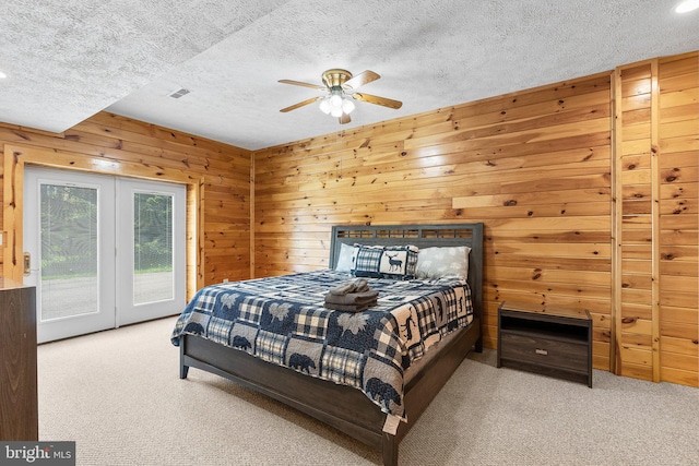 bedroom with access to outside, wood walls, ceiling fan, and carpet flooring