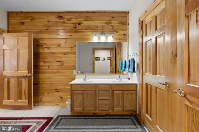 bathroom with tile patterned flooring, vanity, wood walls, and a textured ceiling