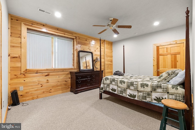 carpeted bedroom featuring ceiling fan and wooden walls