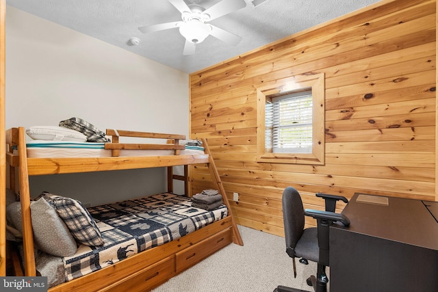 bedroom featuring wood walls, ceiling fan, light carpet, and a textured ceiling