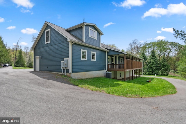 view of side of property with central AC, a lawn, and a garage