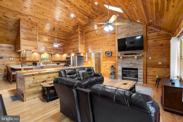 living room with high vaulted ceiling, ceiling fan, and wooden walls