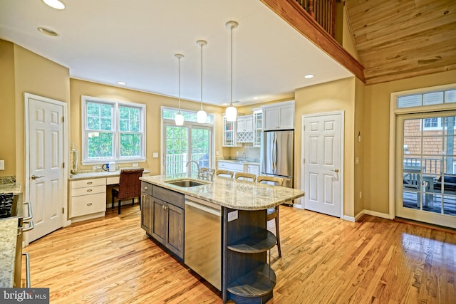 kitchen featuring pendant lighting, a kitchen island with sink, sink, white cabinets, and appliances with stainless steel finishes