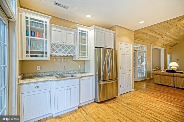 kitchen featuring light hardwood / wood-style floors, white cabinetry, stainless steel refrigerator, a healthy amount of sunlight, and sink