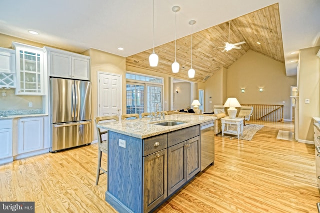 kitchen with appliances with stainless steel finishes, white cabinets, ceiling fan, a kitchen island with sink, and sink