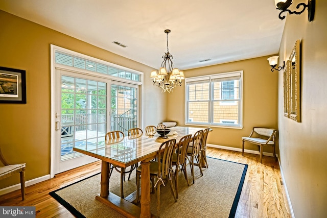 dining room featuring light wood-type flooring, a notable chandelier, and a wealth of natural light