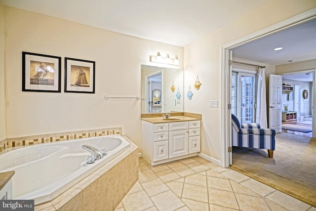 bathroom with tiled tub, vanity, and tile patterned floors