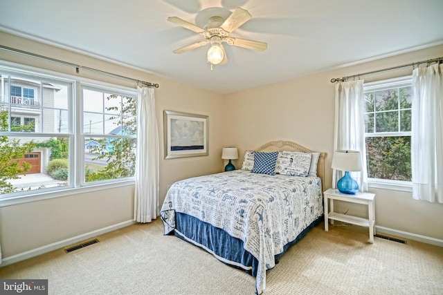 carpeted bedroom featuring multiple windows and ceiling fan