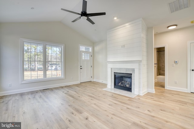 unfurnished living room featuring a fireplace, lofted ceiling, light hardwood / wood-style flooring, and ceiling fan